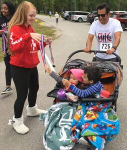 Girl from c-6 educational foundation handing out metals to kids